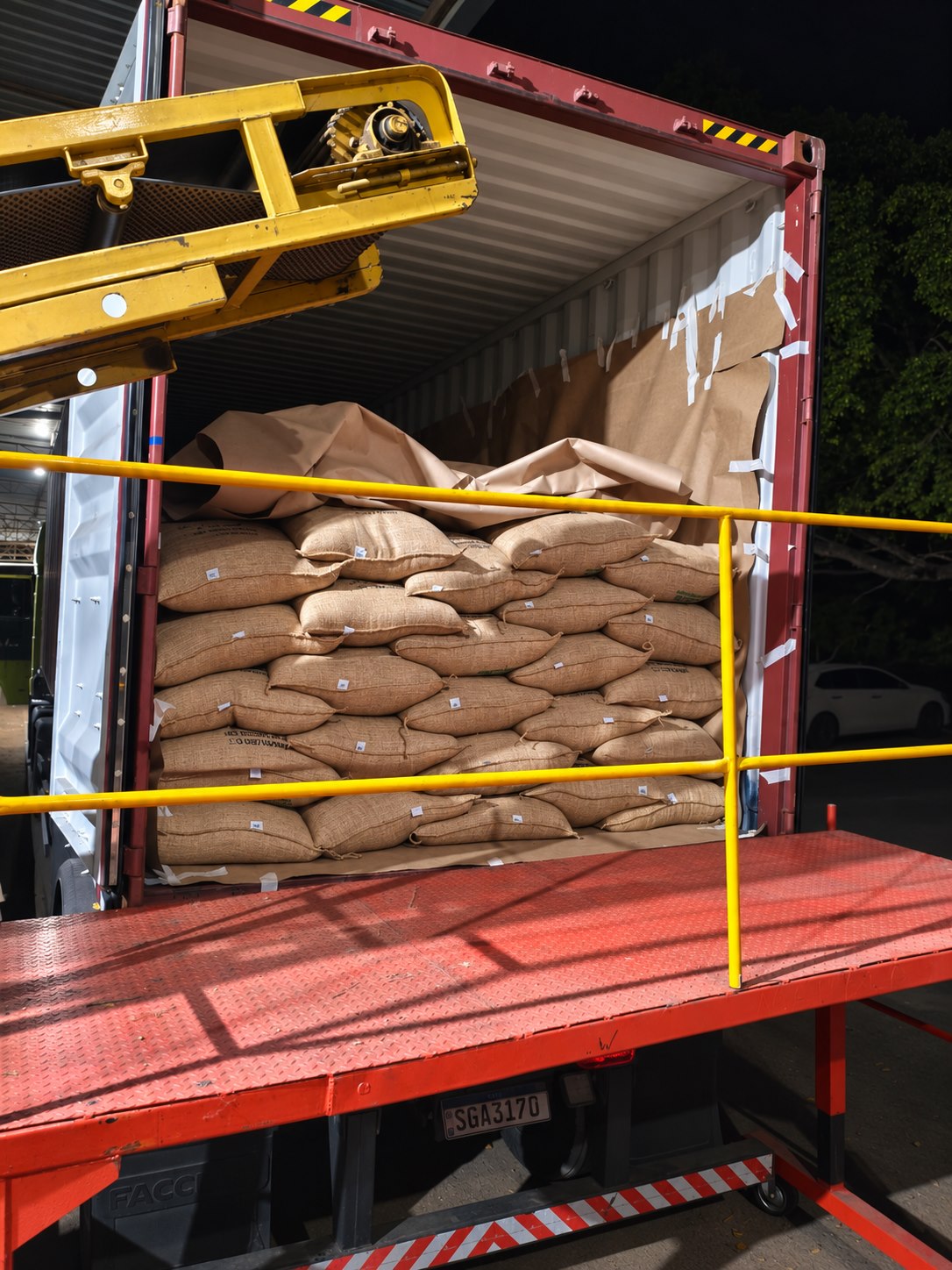 Sacas de café empilhadas em contêiner durante carregamento noturno